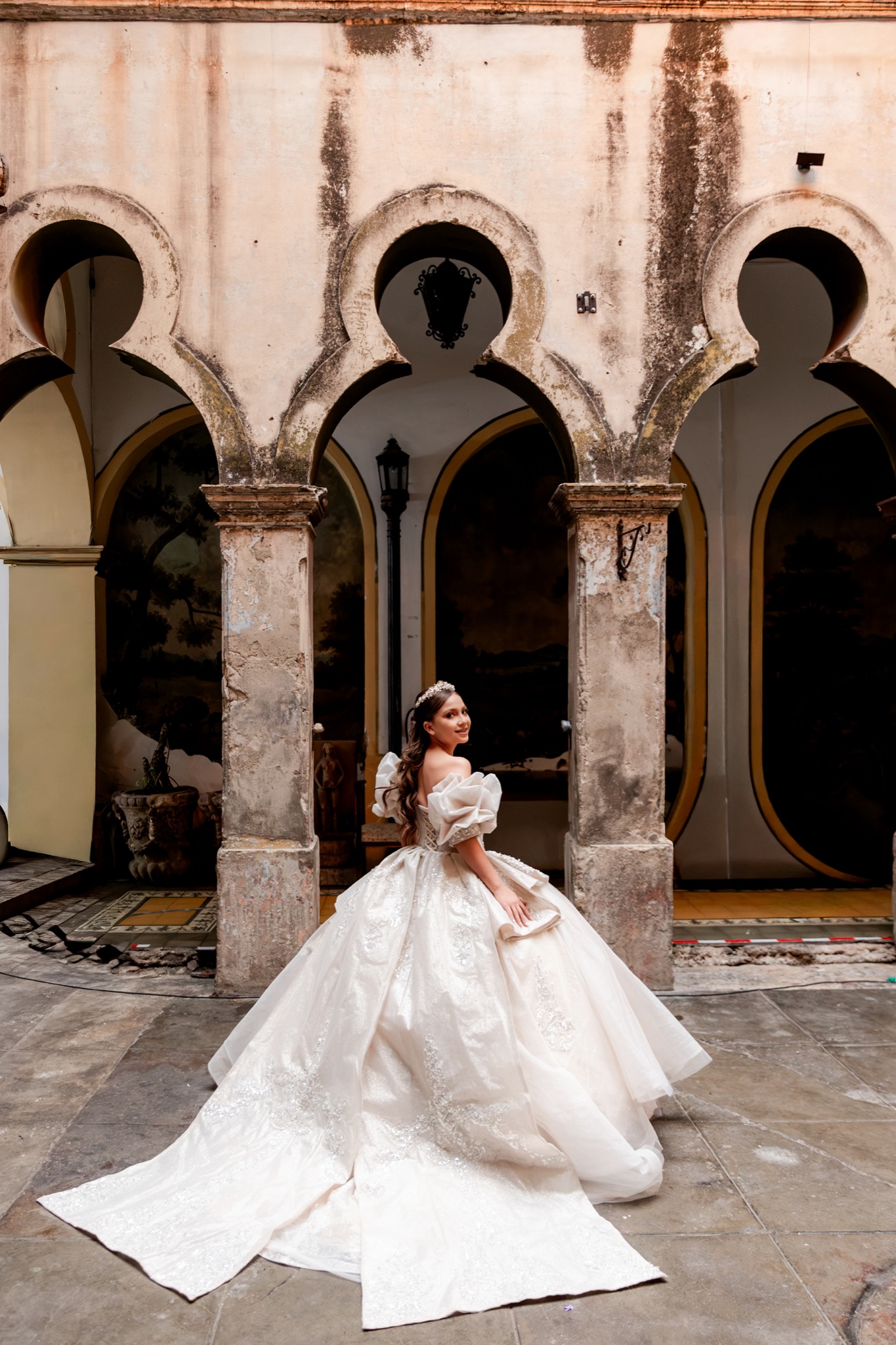 Karol con la cola del vestido extendida en el patio de arcos moriscos del Palacio de las Vacas